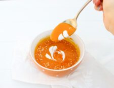 sopa crema de calabaza decorada con corazones de crema en tazón naranja