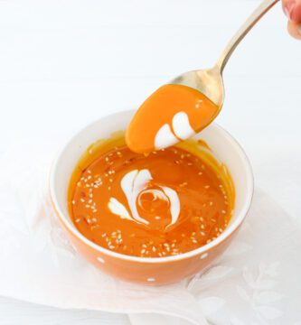 sopa crema de calabaza decorada con corazones de crema en tazón naranja